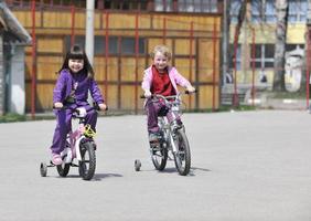 glückliche kindergruppe, die lernt, fahrrad zu fahren foto