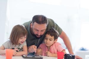 alleinerziehender vater zu hause mit zwei kindern, die spiele auf dem tablet spielen foto