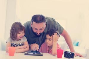 alleinerziehender vater zu hause mit zwei kindern, die spiele auf dem tablet spielen foto