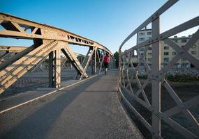 Frau, die am sonnigen Morgen über die Brücke joggt foto