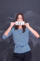 Frau hält eine Banknote vor Kreidezeichenbrett foto