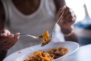 eine junge Afroamerikanerin, die Pasta isst foto