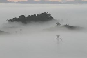 Stromleitungen und Masten, die aus dem Nebel auftauchen foto