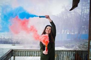 junges Mädchen mit blauer und roter Rauchbombe in den Händen. foto