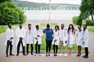 Gruppe afrikanischer Medizinstudenten posierte im Freien in weißen Laborkitteln. foto