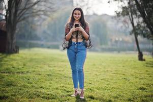 hübsches latino-model-mädchen aus ecuador wear auf jeans posierte auf der straße mit handy. foto