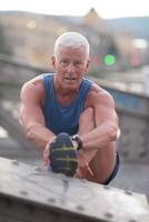 gutaussehender Mann, der sich vor dem Joggen streckt foto