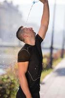 Mann gießt Wasser aus Flasche auf seinen Kopf foto