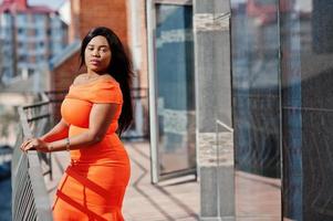 afroamerikanerfrau modell xxl im orangefarbenen kleid. foto