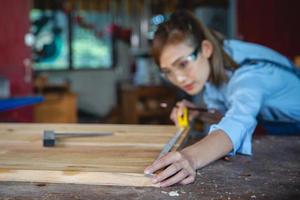 Frau arbeitet in einer Tischlerei. Tischler, der in der Tischlerei an Holzbearbeitungsmaschinen arbeitet. foto