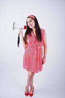 Porträt einer jungen schönen Frau in rotem Kleid, die in ein Megaphon spricht. foto