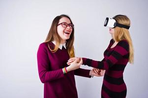 Zwei Mädchen in lila Kleidern probieren im Studio eine Virtual-Reality-Brille aus. foto