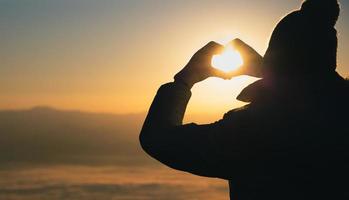 Frau, die bei Sonnenaufgang Herzform macht, Gott ist Liebeskonzept, Herzform, Bergtourismus, Symbol der Liebe, die Manifestation der Liebe, Ausdruck von Gefühlen. Liebe zur Natur, foto