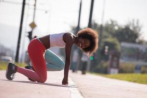 Porträt einer sportlichen jungen afroamerikanischen Frau, die sich im Freien ausdehnt foto
