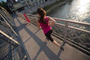 Frau, die am sonnigen Morgen über die Brücke joggt foto