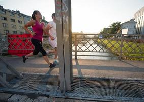 junges Paar joggt über die Brücke in der Stadt foto