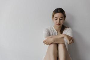 asiatische frau, die auf dem hausbereich sitzt, fühlt sich traurig, müde und besorgt über depressionen, psychische gesundheitsprobleme und herzzerreißendes konzept. foto