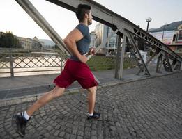 Mann, der am sonnigen Morgen über die Brücke joggt foto