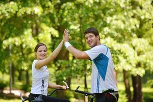 Glückliches Paar, das im Freien Fahrrad fährt foto