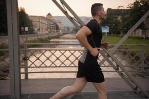 Mann, der am sonnigen Morgen über die Brücke joggt foto