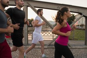 Gruppe junger Leute, die über die Brücke joggen foto