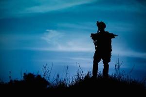 Silhouette eines Militärsoldaten oder Offiziers mit Waffen in der Nacht. foto