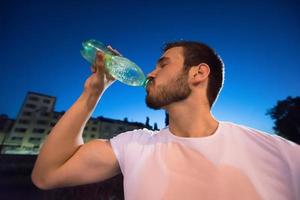 Mann trinkt Wasser nach dem Laufen foto
