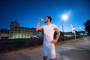 Mann trinkt Wasser nach dem Laufen foto