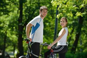 Glückliches Paar, das im Freien Fahrrad fährt foto