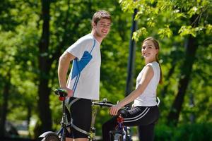 Glückliches Paar, das im Freien Fahrrad fährt foto