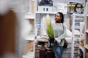 afrikanische frau, die topfdekoration für ihre wohnung in einem modernen einrichtungsgeschäft wählt. foto