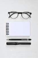 Brille, leerer Notizblock, Stift und Druckbleistift foto