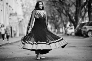 hübsches indisches mädchen im schwarzen saree-kleid posierte im freien auf der herbststraße. foto