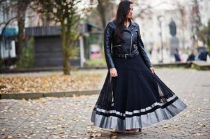 hübsches indisches mädchen in schwarzem saree-kleid und lederjacke posierte im freien auf der herbststraße. foto