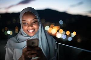 junge muslimische frau auf der straße nachts mit telefon foto