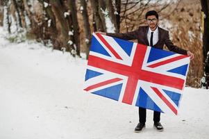 stilvoller indischer mann im anzug mit großbritannien-flagge, die am wintertag im freien gestellt wird. foto