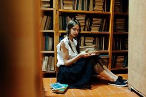 Mädchen mit Zöpfen in weißer Bluse in der alten Bibliothek. foto