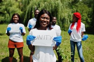 Eine Gruppe glücklicher afrikanischer Freiwilliger hält ein leeres Brett mit einem Einheitszeichen im Park. afrika-freiwilligenarbeit, wohltätigkeit, menschen und ökologiekonzept. foto