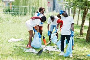 gruppe glücklicher afrikanischer freiwilliger mit müllsäcken, die bereich im park reinigen. afrika-freiwilligenarbeit, wohltätigkeit, menschen und ökologiekonzept. foto