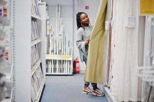 Afrikanische Frau wählt Tüll im Badezimmer für ihre Wohnung in einem modernen Einrichtungshaus. foto