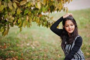 Porträt eines jungen schönen indischen oder südasiatischen Teenager-Mädchens im Kleid, das im Herbstpark posiert. foto