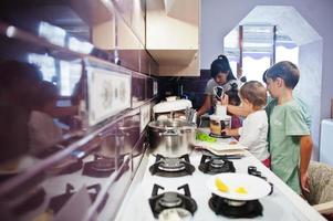 mutter mit kindern, die in der küche kochen, glückliche kindermomente. mit einem Mixer arbeiten. foto