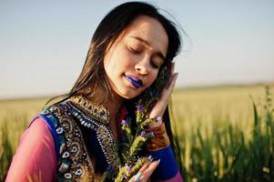 zartes indisches mädchen im saree, mit violetten lippen, die bei sonnenuntergang auf dem feld posierten. modisches Indien-Modell. foto