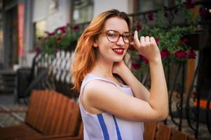 attraktive rothaarige frau mit brille, die auf der straße der frühlingsstadt posiert. foto