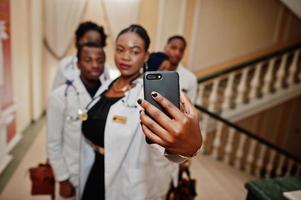 gruppe afrikanischer arztstudenten innerhalb der medizinischen universität, die selfie am telefon machen. foto