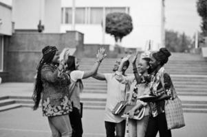 Gruppe von fünf afrikanischen College-Studenten, die gemeinsam Zeit auf dem Campus des Universitätshofs verbringen. Schwarze Afro-Freunde studieren und geben sich High Five. foto