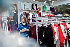 Blondes Mädchen im blauen Kleid in der Boutique des Bekleidungsgeschäfts. foto