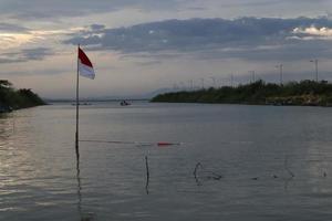 indonesische flagge, die am nachmittag vor dem hintergrund des sees und des himmels flattert foto