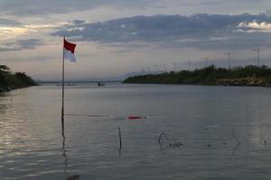 indonesische flagge, die am nachmittag vor dem hintergrund des sees und des himmels flattert foto