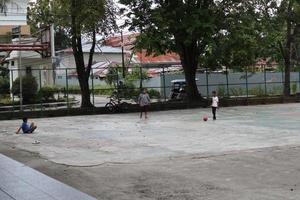 gorontalo-indonesien, juni 2022 - kinder üben tagsüber fußball auf einem basketballplatz foto